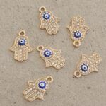 DIJE METAL STRASS, MANO DE FÁTIMA OJO TURCO COLGANTE X 12 UNIDADES. (EMA 26-35)